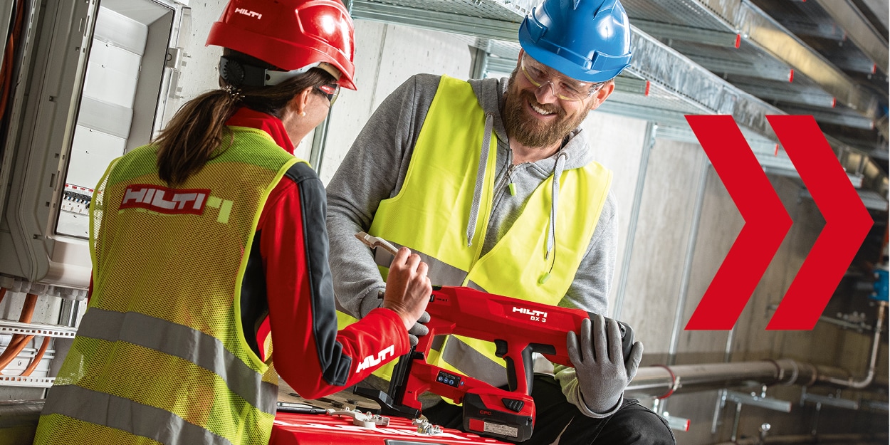 image of 2 people in hi vis vests whilst 1 person holds a red Hilti tool